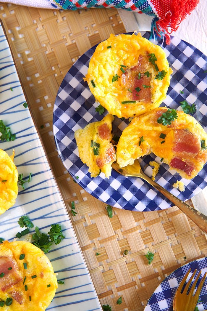 Overhead shot or two bacon egg muffins on a blue and white plate.