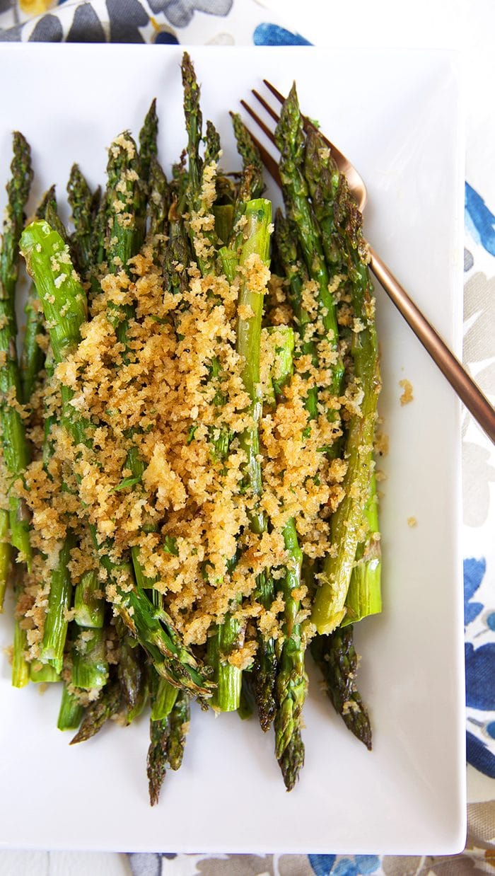 Overhead shot of baked asparagus on a white platter with a crispy panko crust.