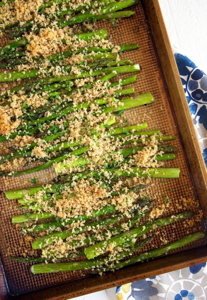 Overhead shot of baked asparagus on a baking sheet with crispy panko topping.