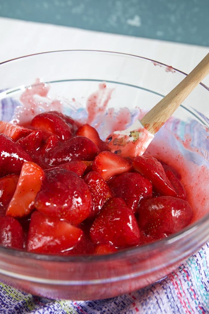 Bowl of strawberries being tossed with strawberry glaze.