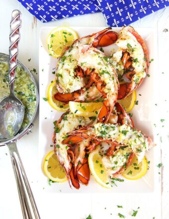 Garlic butter sauce in a saucepan next to a plate of grilled lobster tails.