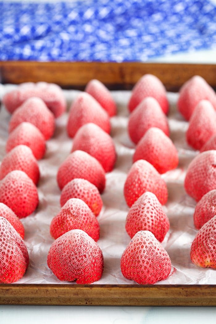 Frozen strawberries arranged on a baking sheet.
