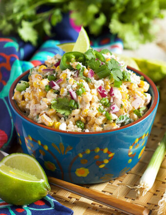 Mexican Street Corn Salad in a blue bowl with a lime in front of it.