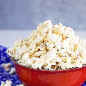 White cheddar popcorn in a red bowl on a blue napkin.