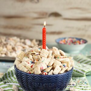 blue bowl with birthday cake puppy chow and a candle.