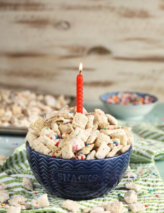 blue bowl with birthday cake puppy chow and a candle.