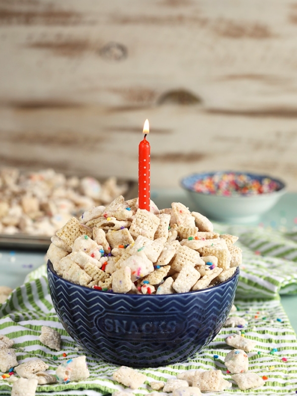 blue bowl with birthday cake puppy chow and a candle.