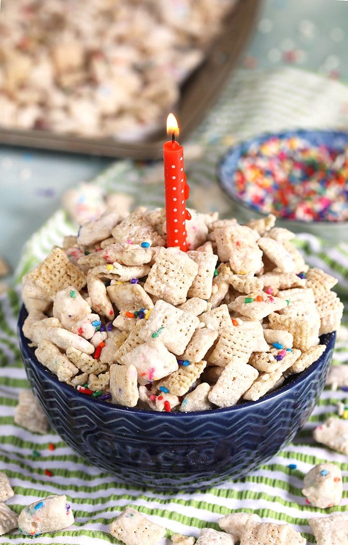 Birthday Cake Puppy Chow in a blue bowl with a pink candle