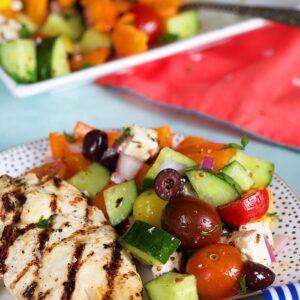 Greek Salad on a white plate with grilled chicken.