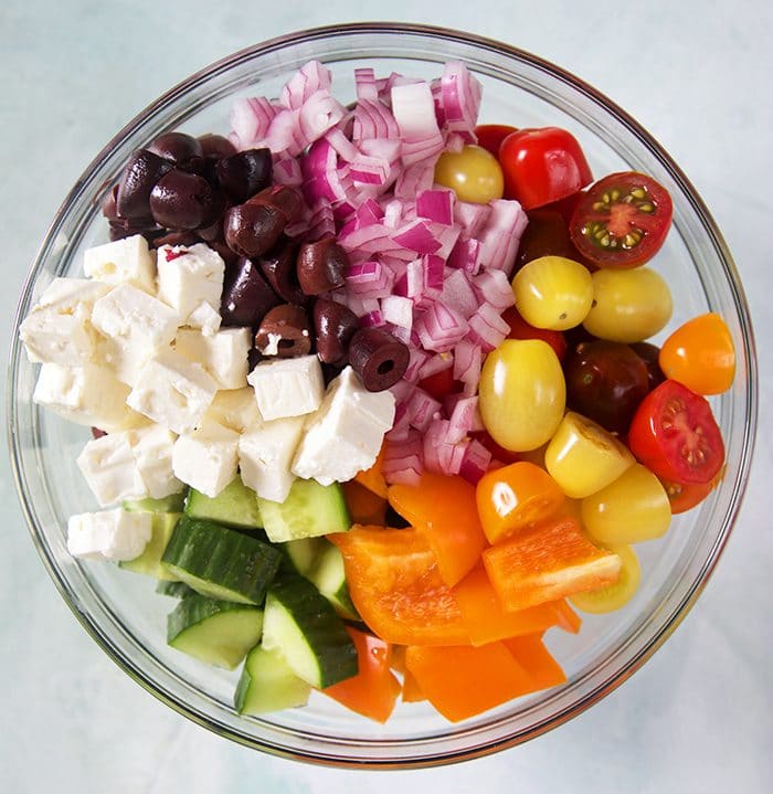 ingredients for greek salad in a glass bowl.