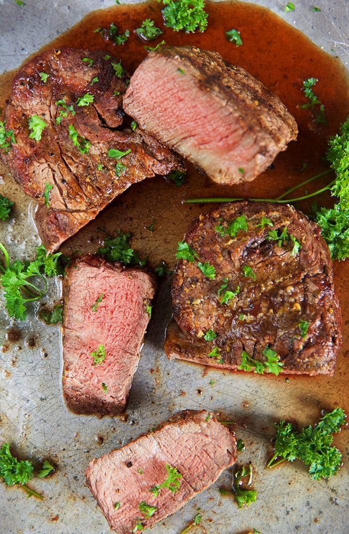 Grilled Filet Mignon on a metal platter with parsley.