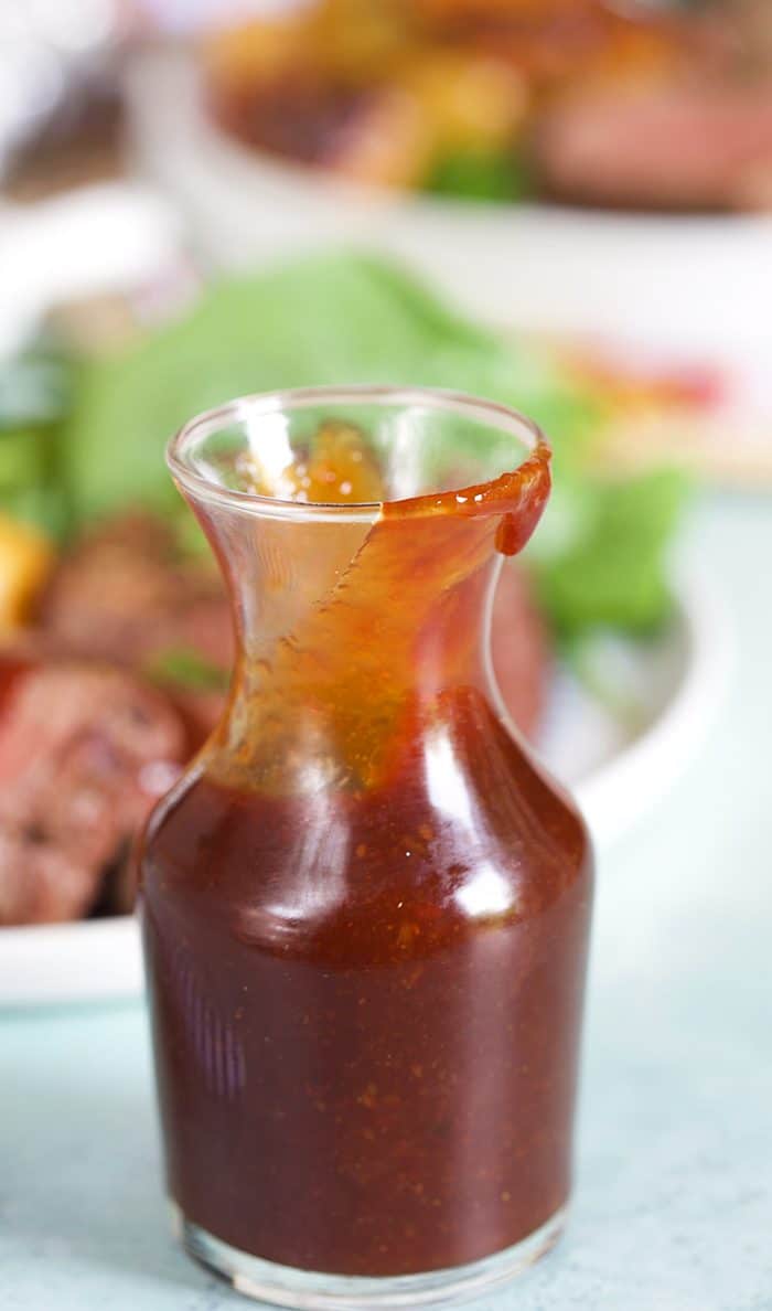 Steak sauce in a small bottle on a blue background.