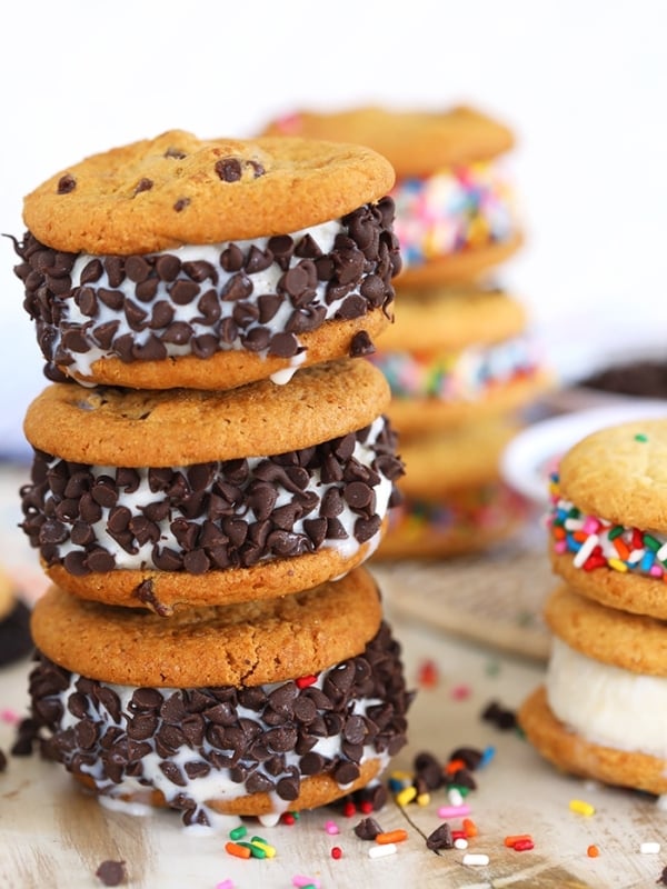 Three chocolate chip cookie ice cream sandwiches stacked.