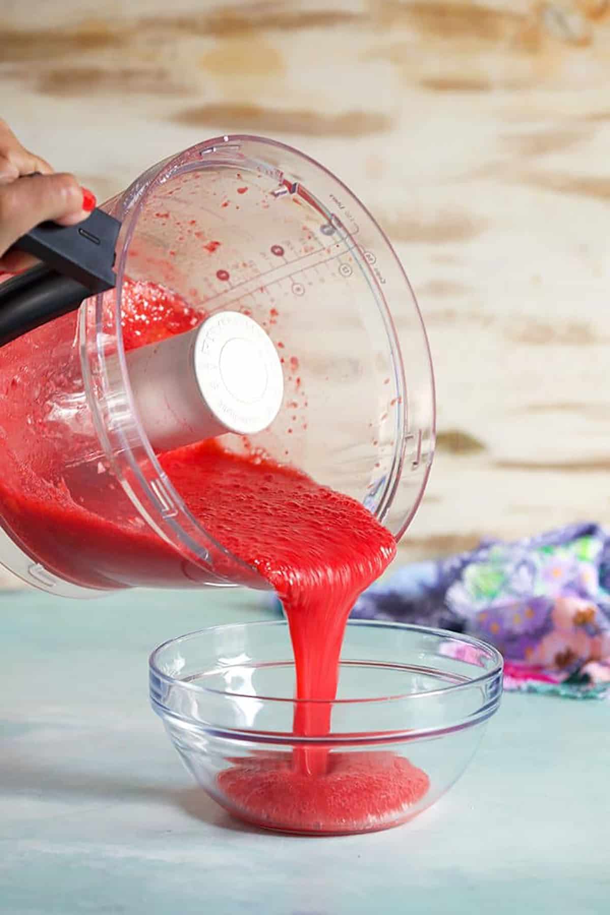 strawberry puree being poured into a small glass bowl.