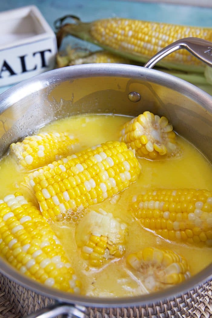 Overhead shot of corn on the cob in a pot of buttery milk.