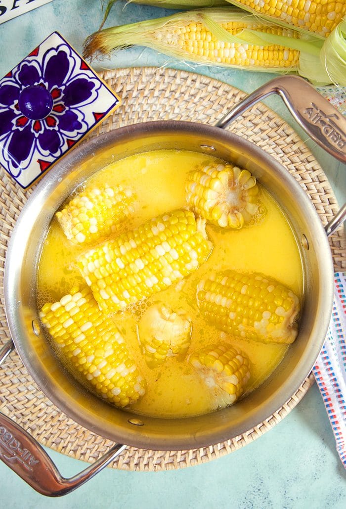 Overhead shot of corn on the cob in a stainless steel pot.