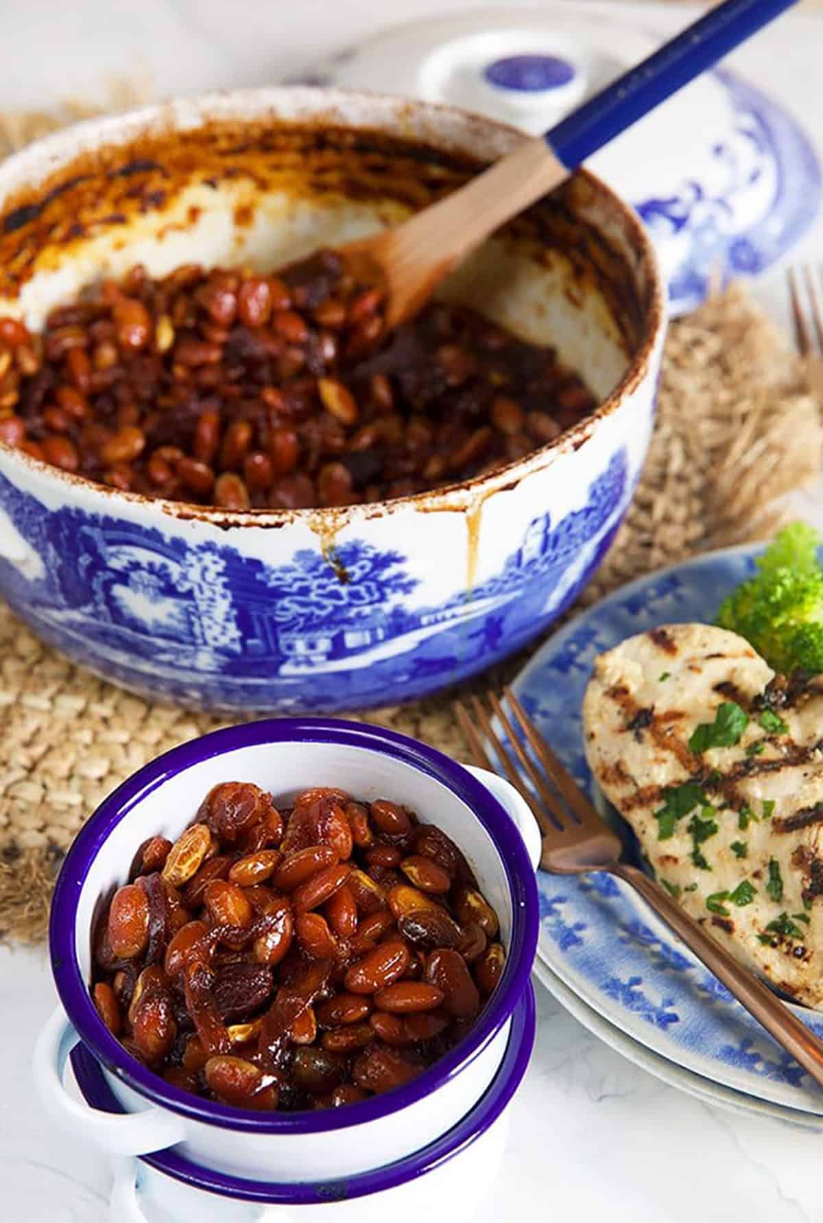 Boston Baked Beans in a white dish with a pot in the background.