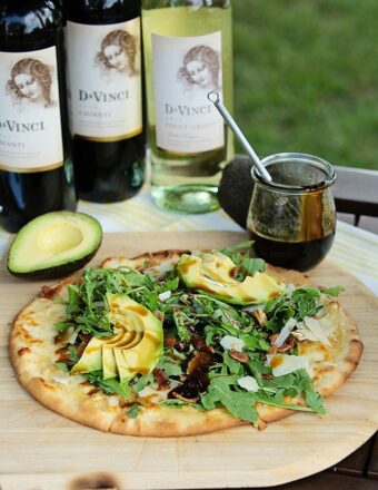 pizza on a wooden pizza peel with arugula and avocado.