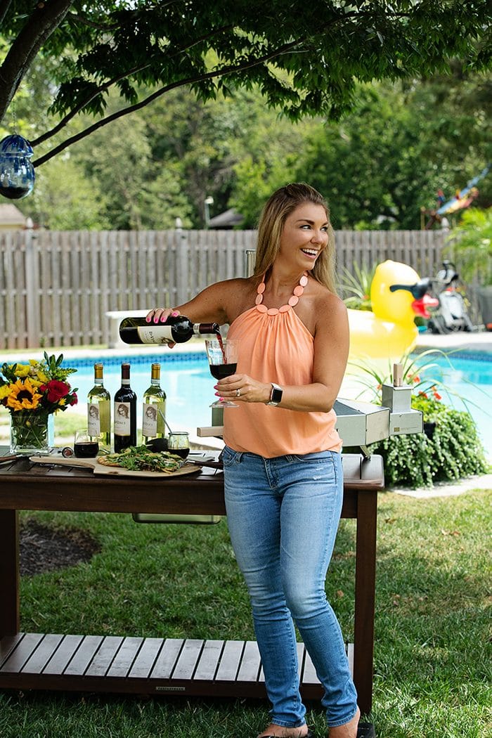Kellie from the Suburban Soapbox pouring a glass of DaVinci Chianti Wine by a pool.