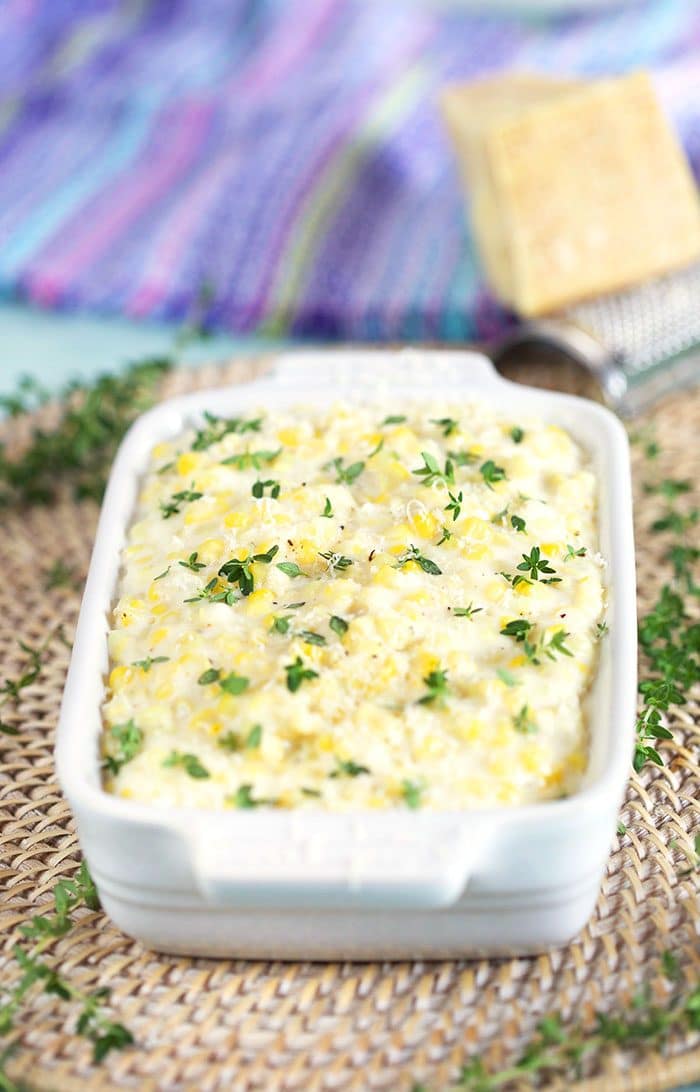 Creamed Corn in a white dish with thyme sprinkled on top.