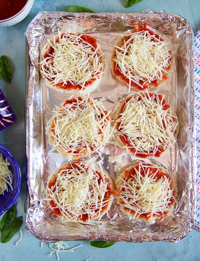 English Muffin Pizzas on a baking sheet with foil prior to baking.