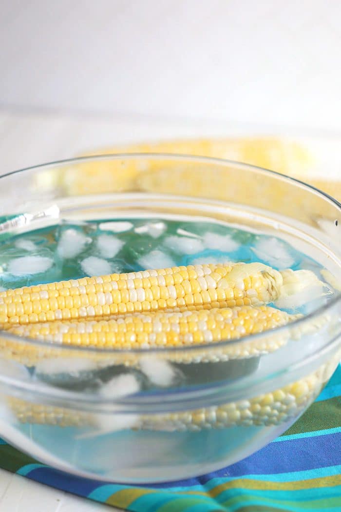 blanching corn on the cob in a glass bowl.