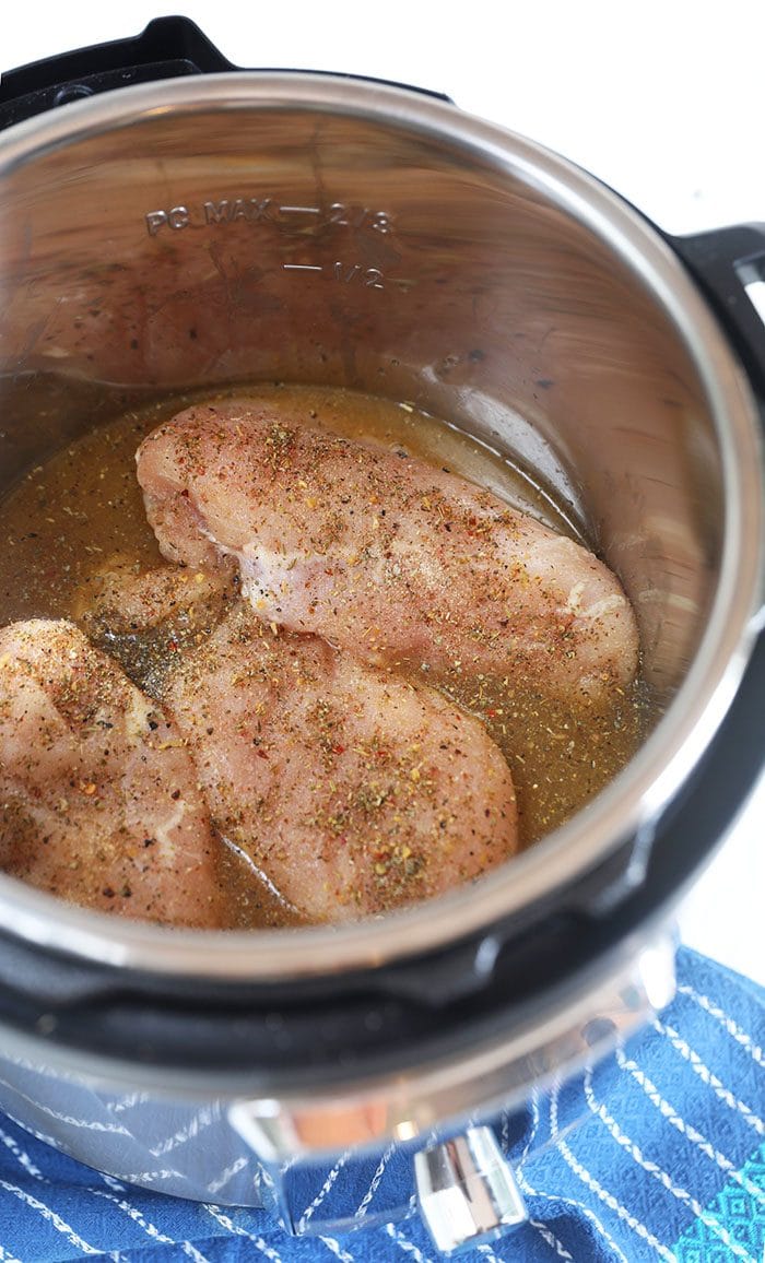 Chicken breasts in chicken stock at the bottom of an Instant Pot.