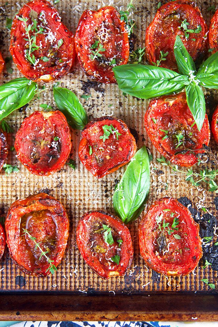 Close up of oven roasted tomatoes with basil and herbs.