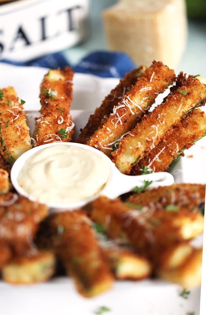 Close up of zucchini fries on a white platter.