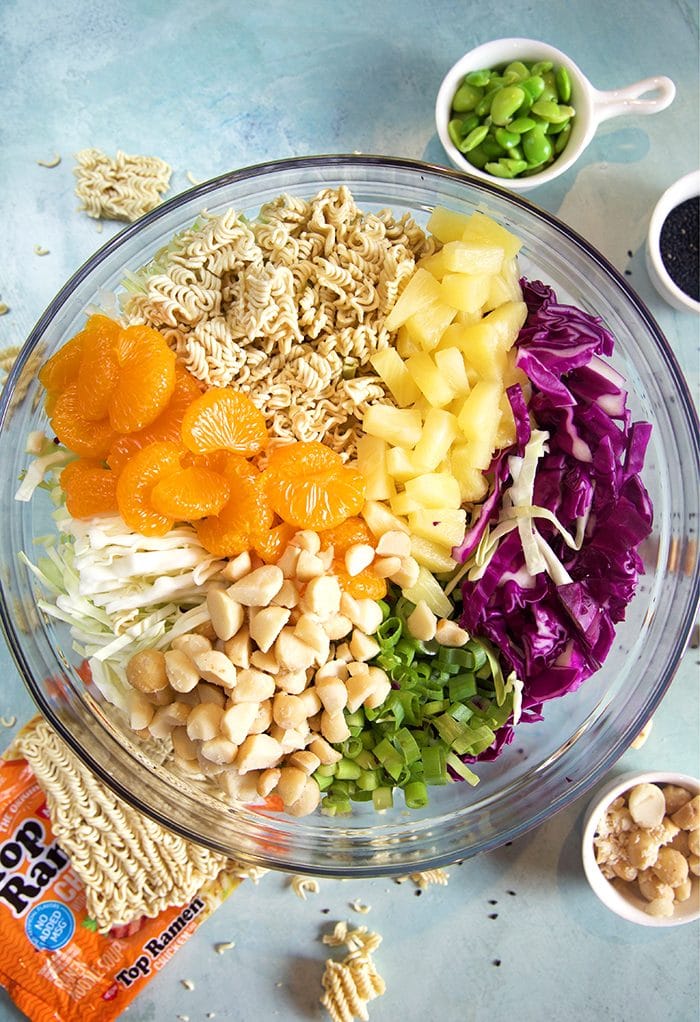 Overhead shot of ramen noodle salad ingredients in a glass bowl.