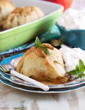 Apple Dumpling on a blue and white plate with a scoop of vanilla ice cream and a white spoon.