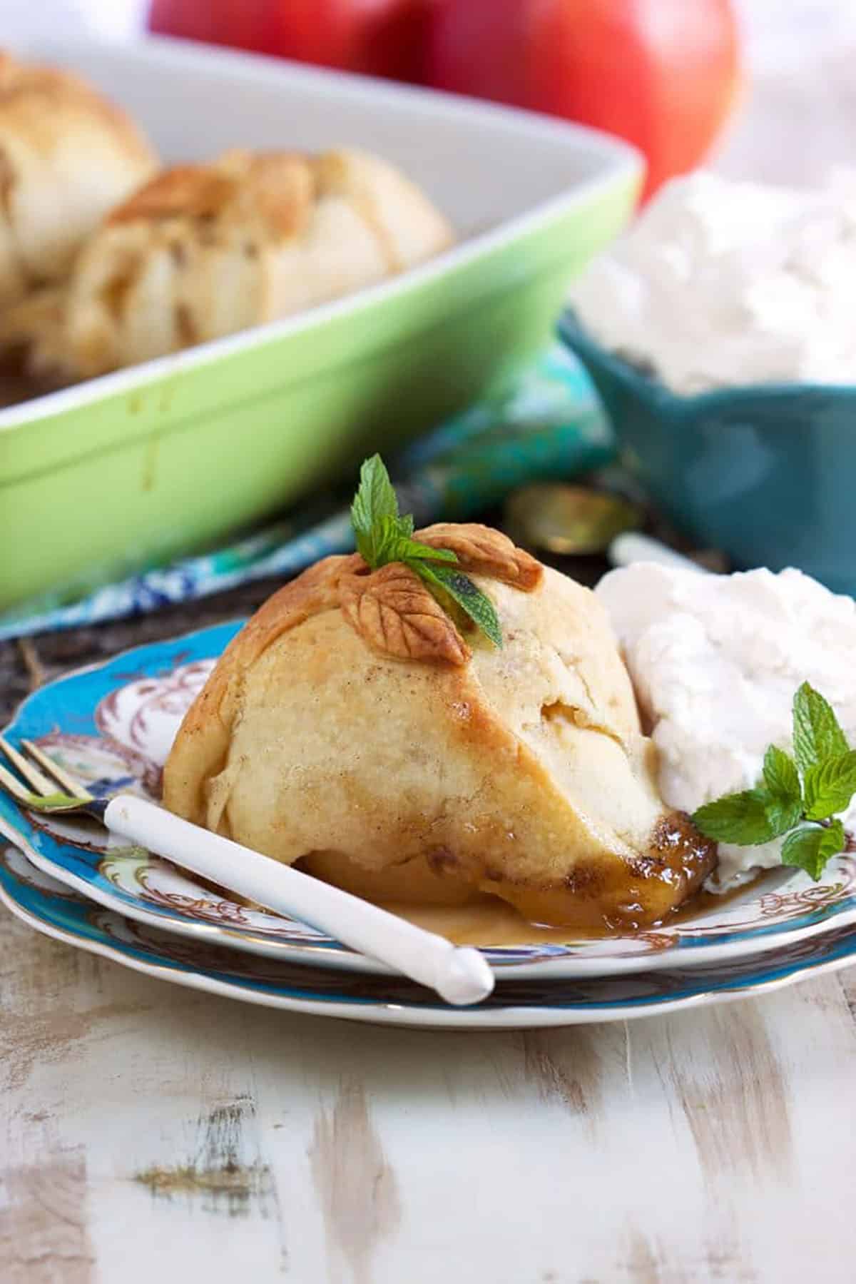 Apple Dumpling on a blue and white plate with a scoop of vanilla ice cream and a white spoon.