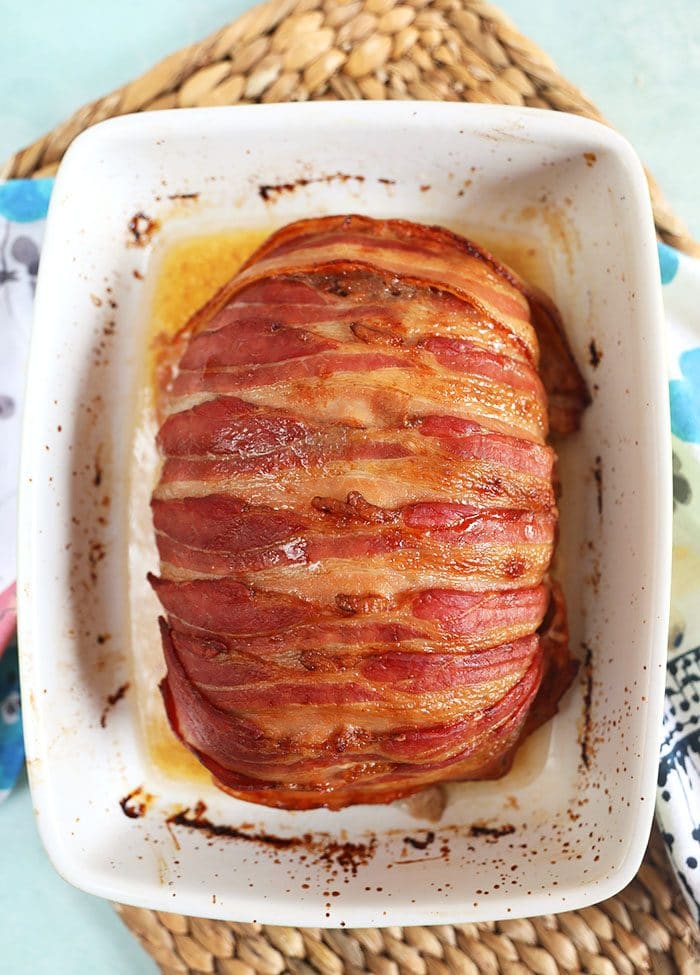 Bacon wrapped meatloaf in a white baking dish.