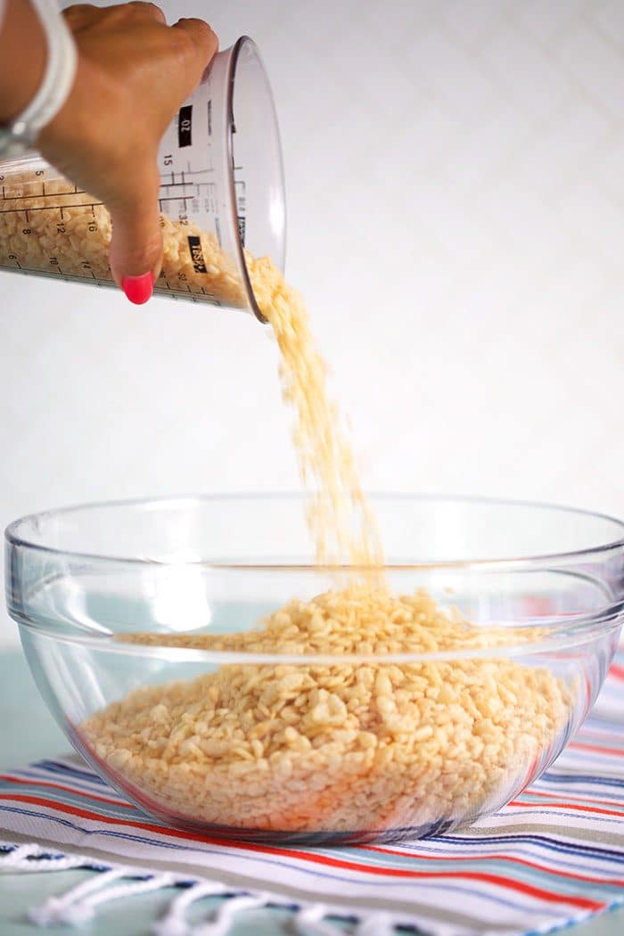 Rice Krispies being poured into a glass bowl.