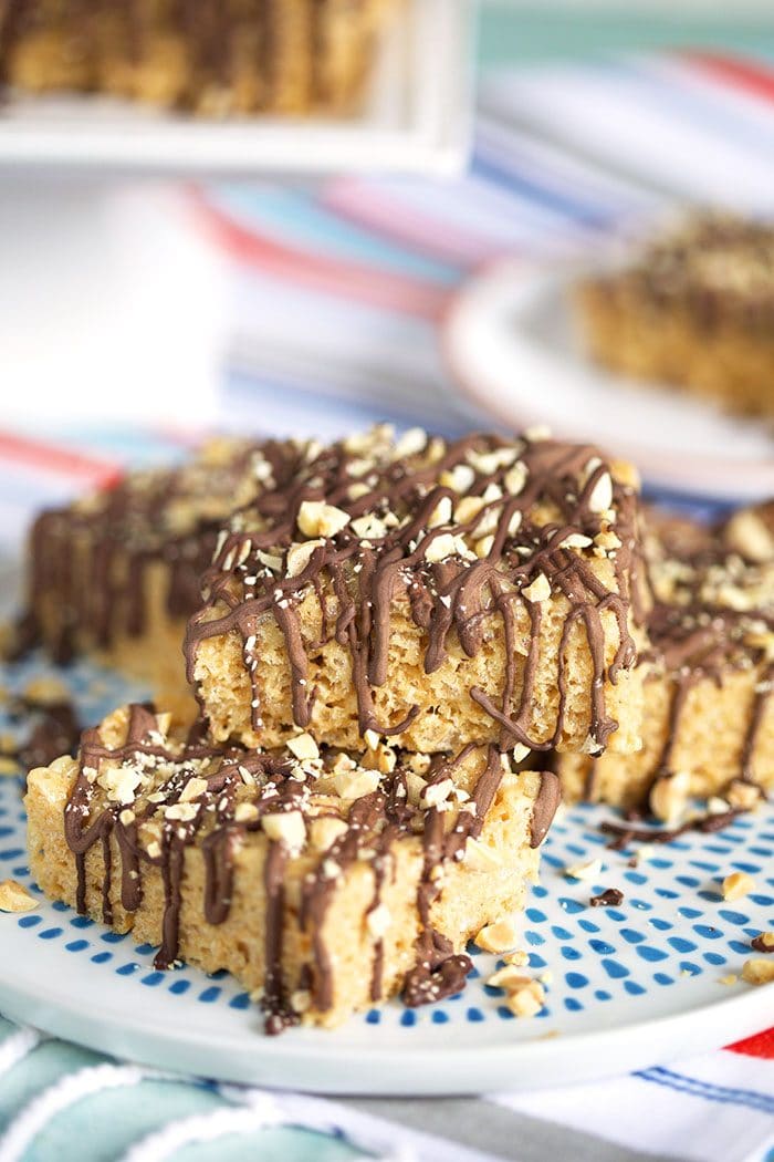 Peanut Butter Rice Krispie Treats stacked on a white plate with blue spots.