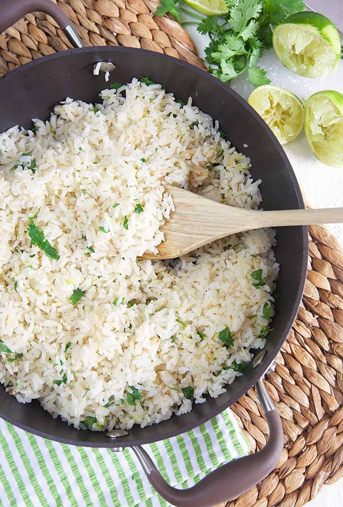 Overhead shot of cilantro lime rice in a pot with a wooden spoon.