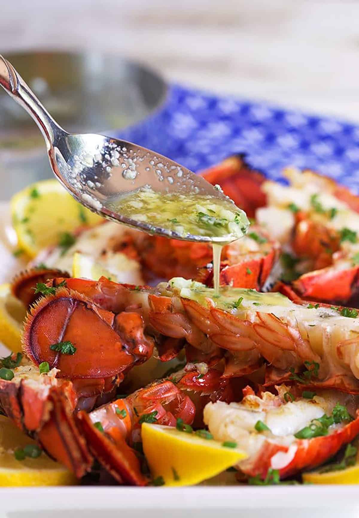 Grilled Lobster Tails with butter sauce being drizzled overtop.
