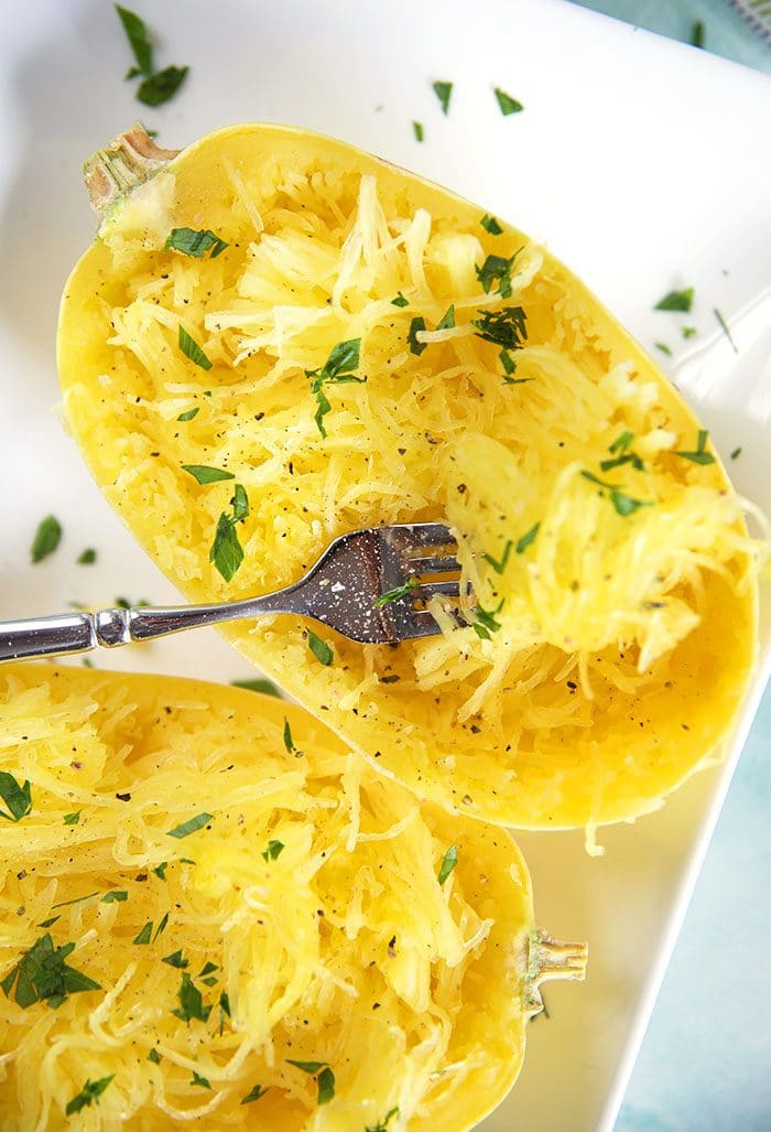 Overhead shot of spaghetti squash with a fork on a white platter.