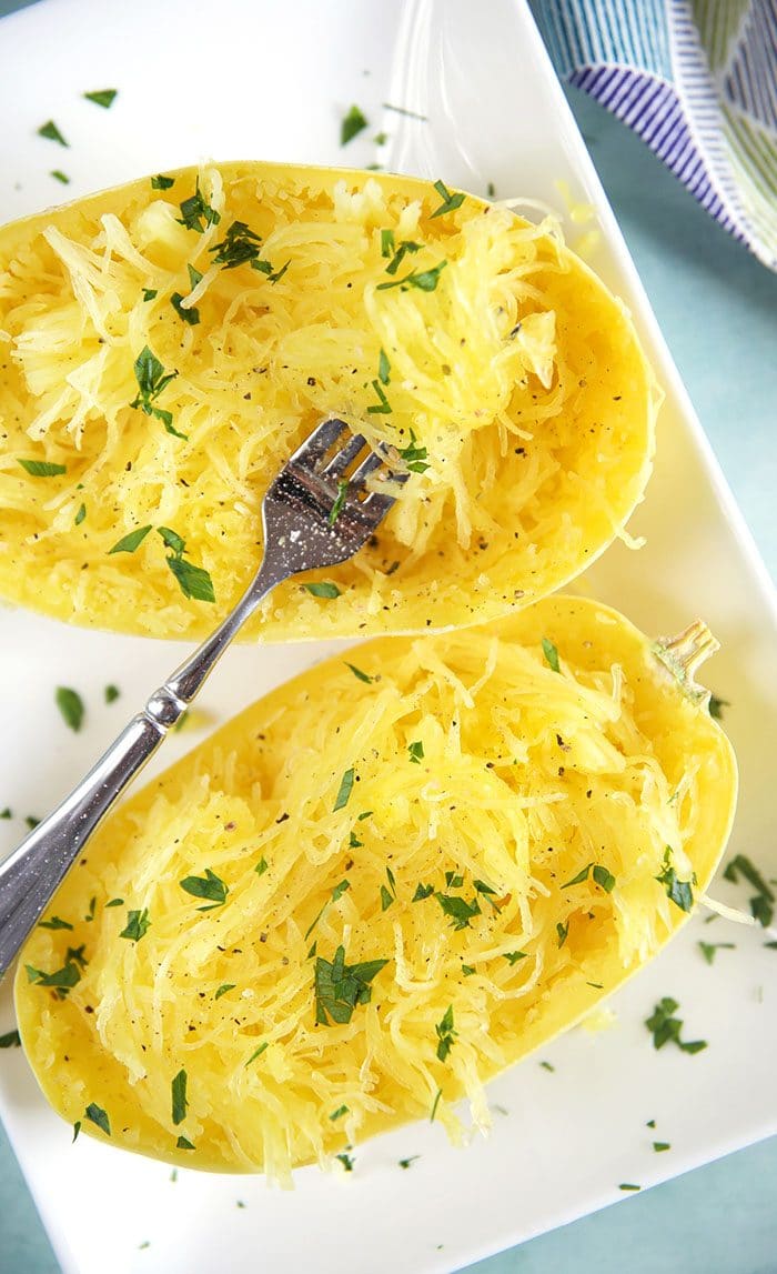 Cooked spaghetti squash with a fork on a white plate.