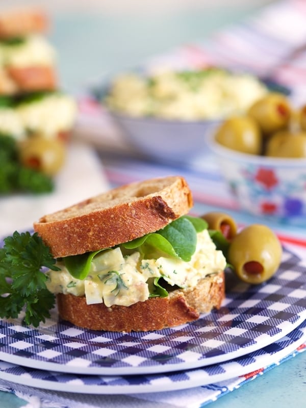 Bacon Horseradish egg salad on mini rye bread with lettuce on a blue and white plate.