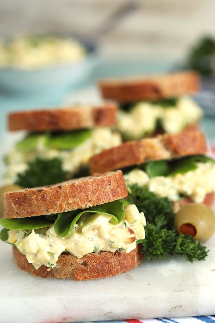 Egg salad sandwiches on a white marble board.