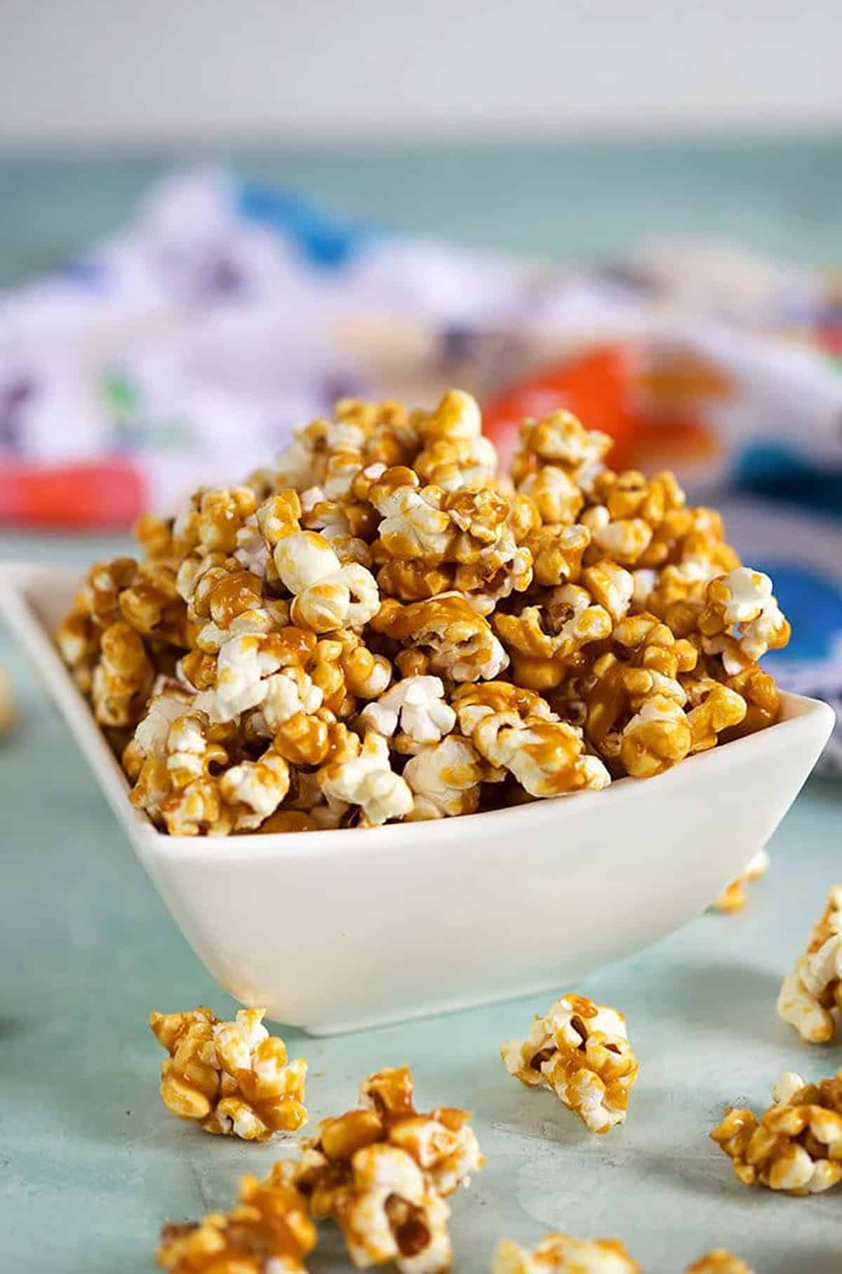 Caramel Popcorn in a white bowl on a blue background.