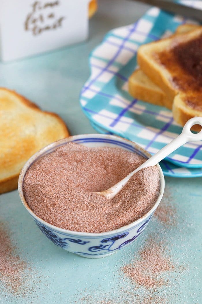 bowl of cinnamon sugar with a white spoon in it.