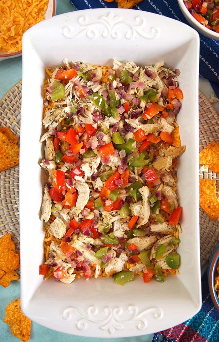 Layer of chicken and vegetables in a white casserole dish.