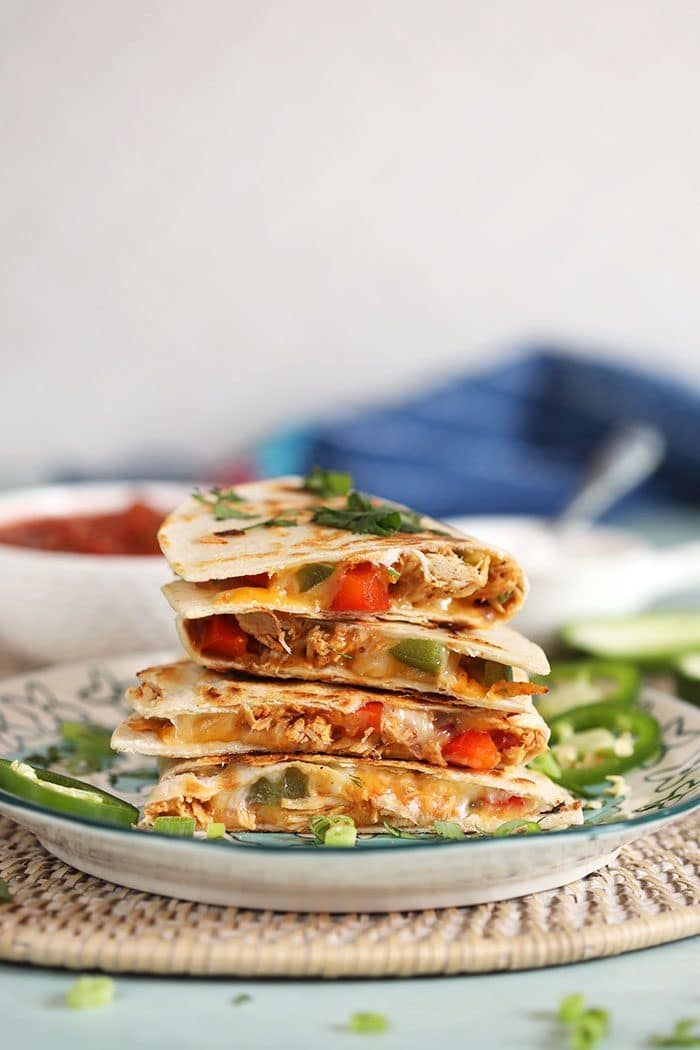 Stack of chicken quesadillas on a plate with cilantro.