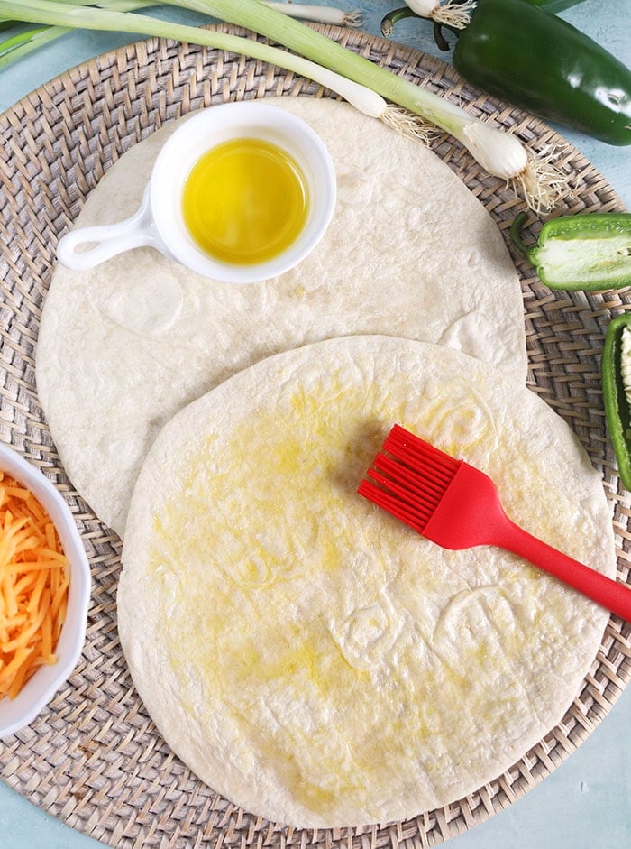 Tortillas with a red brush and a bowl of oil.
