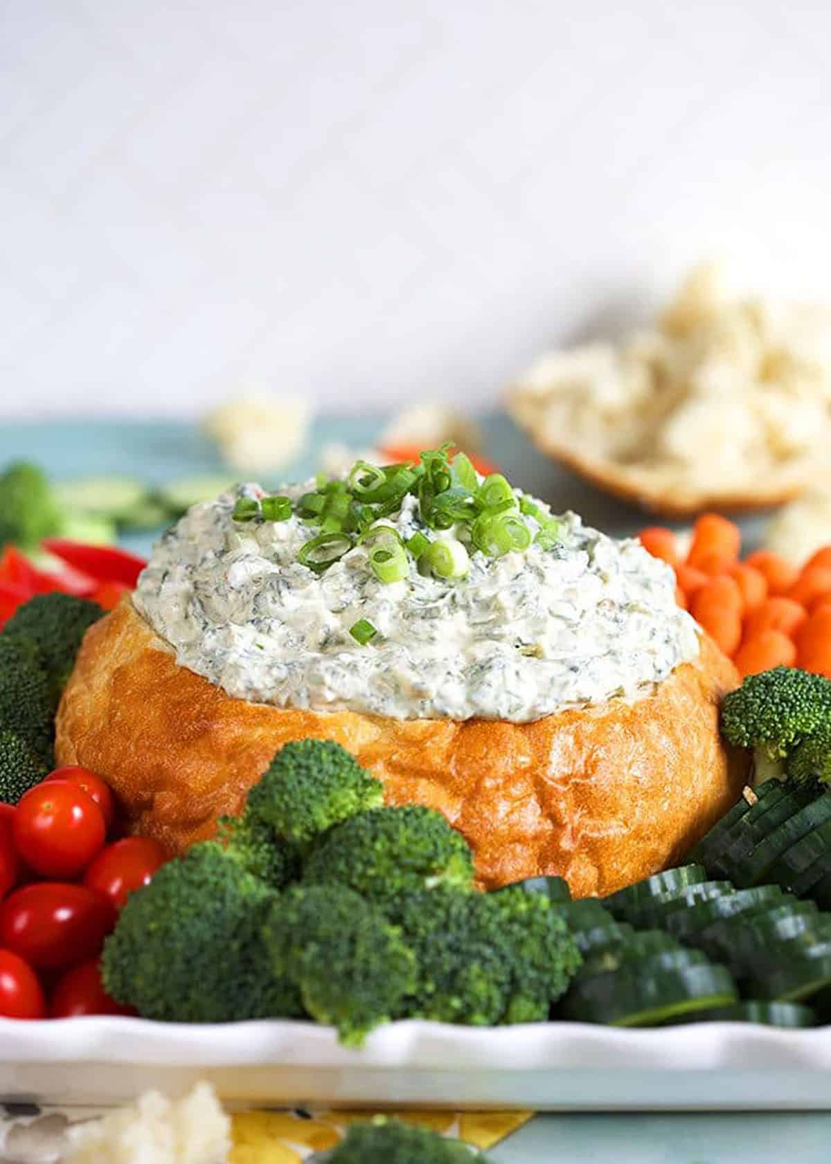 Knorr Spinach Dip in a white bread bowl with vegetables around the bottom.