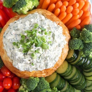 Overhead shot of Knorr Spinach Dip in a bread bowl with vegetables on a platter.