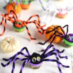 Play Doh spiders on a white background with pumpkins.
