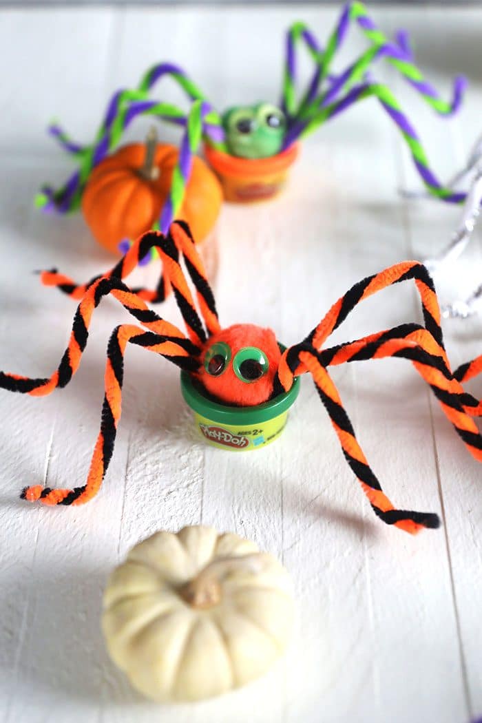 Play doh spiders on a white background with a white pumpkin.